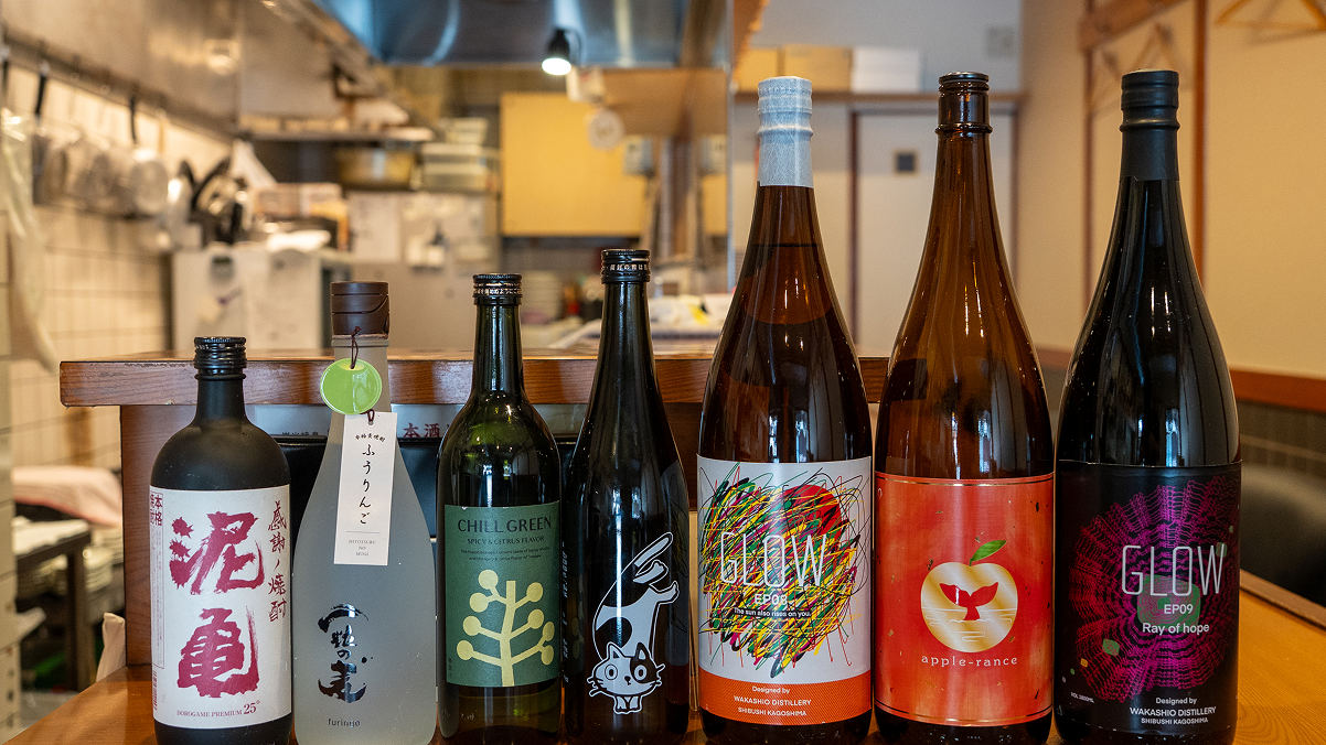 窓辺のカウンターに並ぶ日本酒の一升瓶
